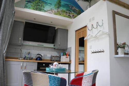 a kitchen with a table and a tv on the ceiling at The Pump-House in Chichester