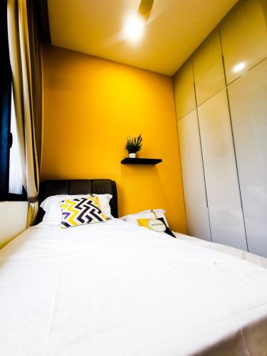 a bedroom with a large bed with a yellow wall at Legoland D'PRISTINE Apartment By TGP in Nusajaya