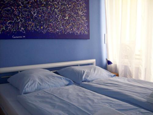 1 cama con 2 almohadas y una pintura en la pared en Miróbile, en Berlín