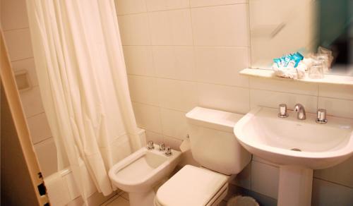 a white bathroom with a toilet and a sink at Hotel Mediterraneo in San Miguel de Tucumán