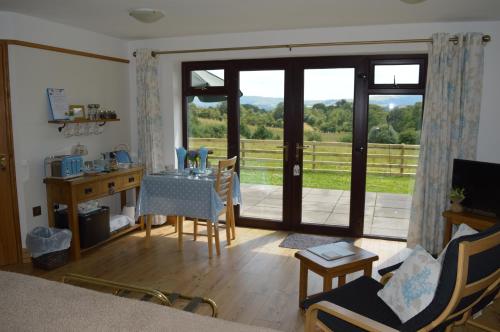 een woonkamer met een tafel en stoelen en een glazen schuifdeur bij Smithfield Farm Bed & Breakfast in Builth Wells