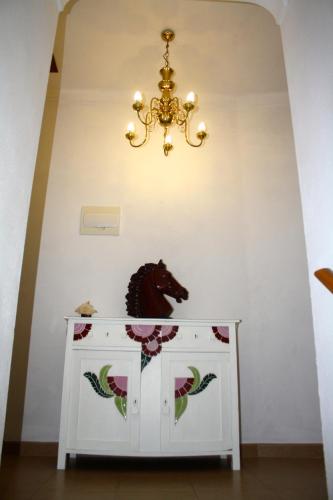 a chandelier above a white cabinet with a horse head on it at Os 5 Sentidos in Mourão