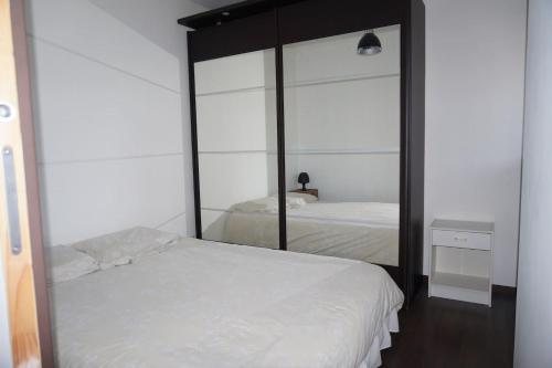 - une chambre avec un miroir et un lit blanc dans l'établissement F1 de 36m2 avec terrasse et parking privatif., à La Roquette-sur-Siagne