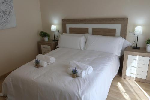 a bedroom with a white bed with towels on it at Apartamento turisticos Puente Romano P4 1-A in Salamanca