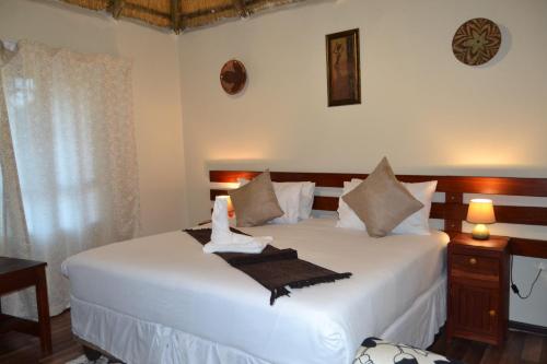 a bedroom with a bed with white sheets and pillows at Chobe Sunset Chalets in Lesoma