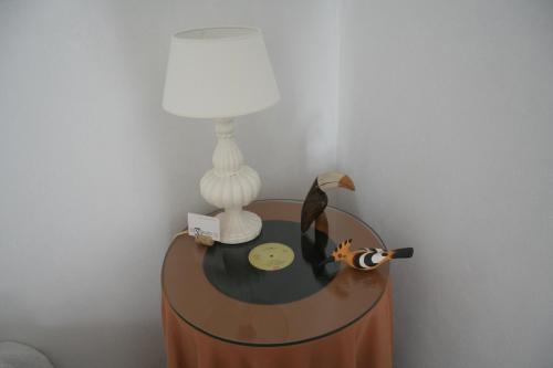 a table with a lamp and a bird on it at Os 5 Sentidos in Mourão