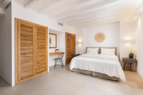 ein weißes Schlafzimmer mit einem Bett und einem Schreibtisch in der Unterkunft Lindian Ethos in Lindos