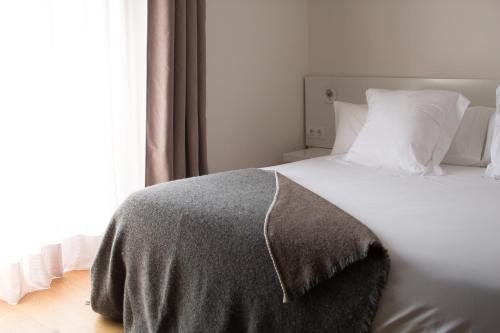 a bed with a gray blanket on it next to a window at Mas Vivent in Vilamaniscle