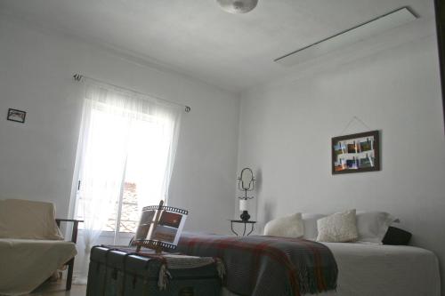 a bedroom with a bed and a chair and a window at Os 5 Sentidos in Mourão