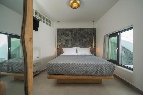 a bedroom with a bed with a stone wall at Secret Spot Luxury Villa in Fira