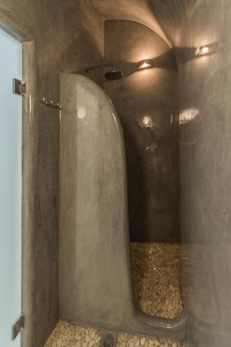 a bathroom with a shower with a stone wall at Secret Spot Luxury Villa in Fira