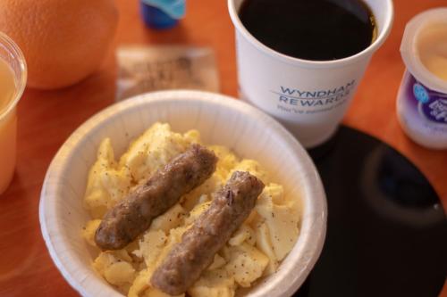 two sausages on a bowl of food with a cup of coffee at Days Inn by Wyndham Prescott in Prescott