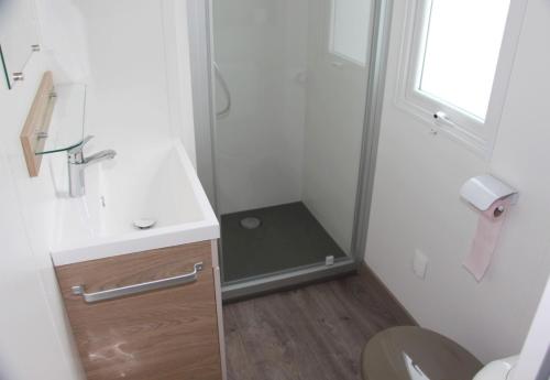 La salle de bains est pourvue d'une douche, d'un lavabo et de toilettes. dans l'établissement Mobile Home Neuf AZ 27, à Fréjus