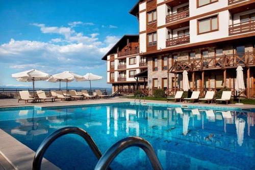 een zwembad tegenover een hotel met stoelen en parasols bij Paradiso Verde (Green Life) in Bansko