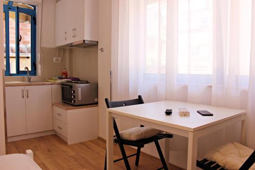 una piccola cucina con tavolo e sedie bianchi di Hercules House a Sarandë