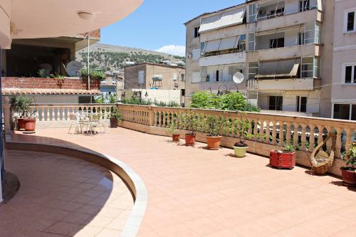 un patio con piante in vaso e un balcone con un edificio di Hercules House a Sarandë