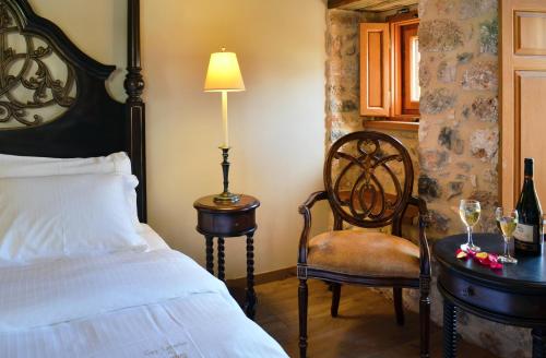 a bedroom with a bed and a table with a chair at Archontiko Chioti in Leonidion