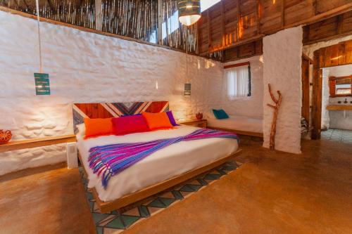Un dormitorio con una cama con almohadas de colores. en Canto del Agua Ecolodge, en Comitán de Domínguez