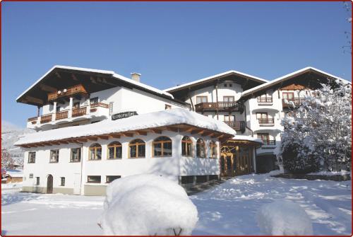 a large white building with snow on the ground at Hotel Metzgerwirt in Kirchberg in Tirol