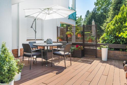 une terrasse avec une table, des chaises et un parasol dans l'établissement eMeN Apartamenty Jastarnia, à Jastarnia