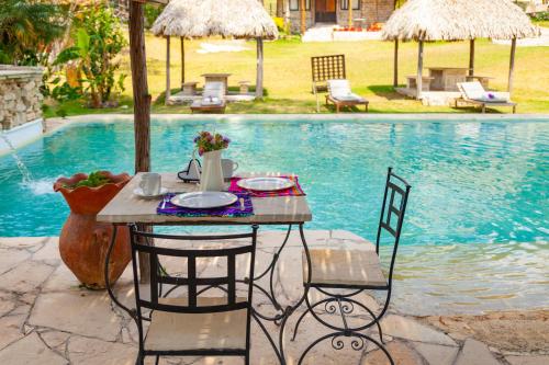 a table and chairs next to a swimming pool at Canto del Agua Ecolodge in Comitán