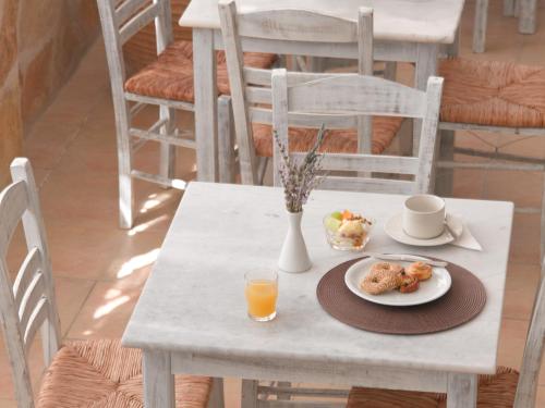 a table with a plate of food and a cup of orange juice at Londos Hotel in Piso Livadi