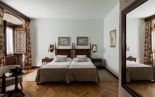 a bedroom with two beds and a mirror at Parador de Pontevedra in Pontevedra