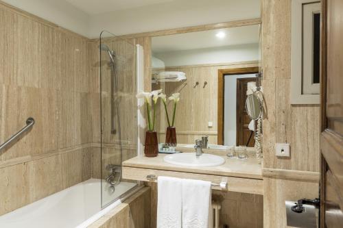 a bathroom with a sink and a tub and a mirror at Parador de Pontevedra in Pontevedra