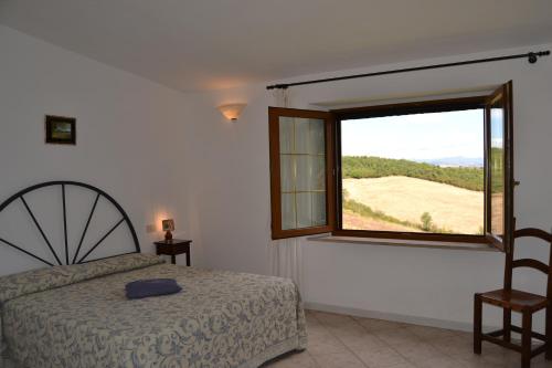 um quarto com uma cama e uma grande janela em Agriturismo Marruchetone Vecchio em Marsiliana
