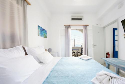 a white bedroom with a bed and a table at Londos Hotel in Piso Livadi