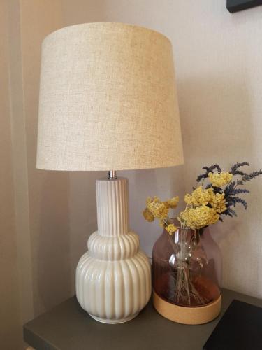 a white lamp on a table next to a vase with flowers at Ferienwohnung Oliver in Fritzlar
