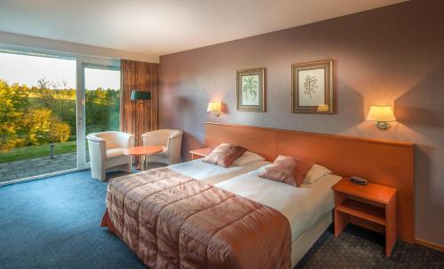 a hotel room with a bed and a large window at Landhotel Heuvelzicht in Schin op Geul