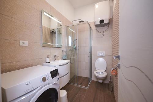 a bathroom with a toilet and a washing machine in it at Apartman Nina in Split