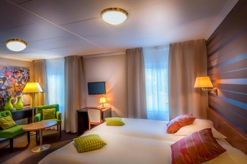 a hotel room with a large white bed and a chair at Landhotel Heuvelzicht in Schin op Geul