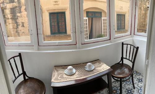 einen Tisch und zwei Stühle in einem Zimmer mit Fenstern in der Unterkunft Santa Marija House in Victoria