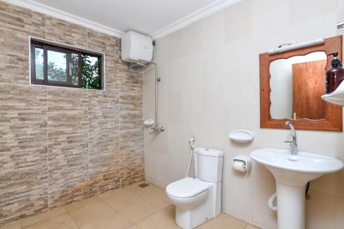 a bathroom with a toilet, sink and mirror at Ifa Beach Resort in Jambiani