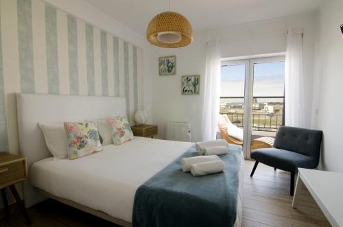 ペニシェにあるSea La Vie Beach House - Penicheのベッドルーム(白いベッド1台、青い椅子付)