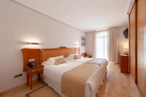 a bedroom with a large white bed and a window at Hotel La Laguna Spa & Golf in Torrevieja