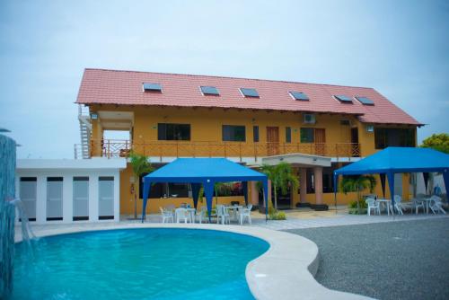a house with a swimming pool with chairs and umbrellas at Hotel Soberao in Esmeraldas