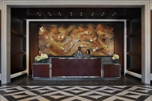 dos personas parados frente a una gran pintura en Four Seasons Hotel One Dalton Street, Boston en Boston