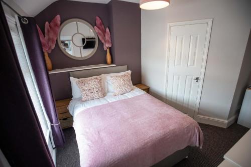 a bedroom with a pink bed and a mirror at The Gables Hotel by Cherish Lewis Blackpool in Blackpool
