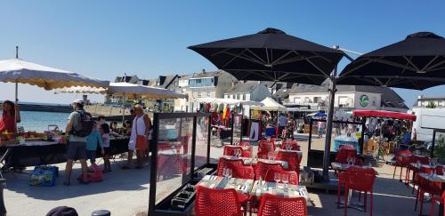 een markt met rode stoelen en parasols op een strand bij " LA BIENVENUE " in Ploemeur