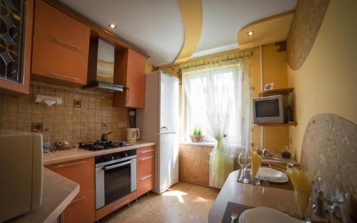 una pequeña cocina con armarios naranjas y una ventana en PaulMarie Apartments on 40 Stroiteley Street, en Soligorsk