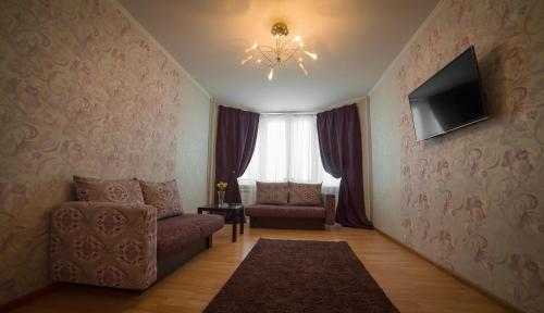 a living room with a couch and a tv and a chair at PaulMarie Apartments on Zaslonova 74 in Soligorsk