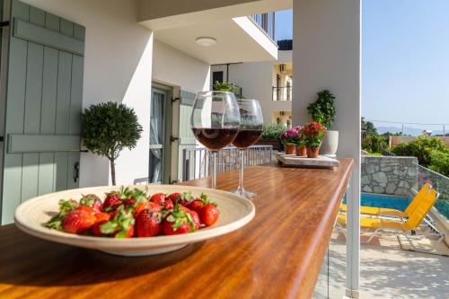 a table with a bowl of strawberries and wine glasses at YaChara Villa in Kissamos