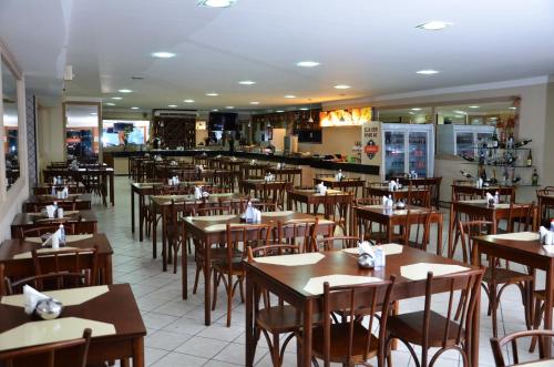 um restaurante cheio de mesas e cadeiras de madeira em Hotel Sabino Palace em Mossoró