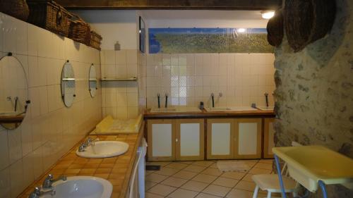 a tiled bathroom with two sinks and two mirrors at Camping jardin La Vie en Vert en Ariège in Augirein
