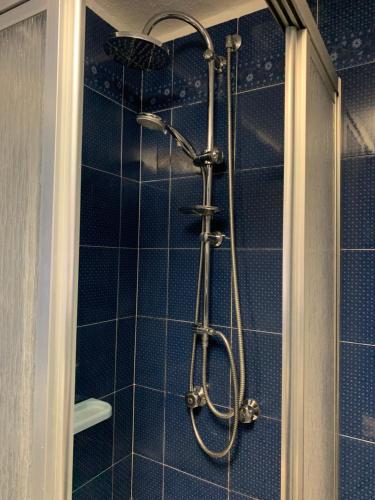 y baño con ducha y azulejos azules. en Il vecchio mulino - Alloggio ad uso turistico - VDA - INTROD - n 0006 en Introd