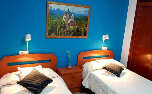 a blue bedroom with two beds and a painting of a castle at RINCON DO MAR ArenaBlanca in A Guarda