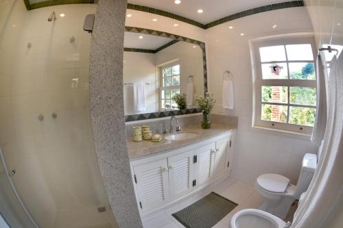 a bathroom with a sink and a toilet and a mirror at Maison de Campagne, Chambres D'Hôtes - Itaipava in Itaipava